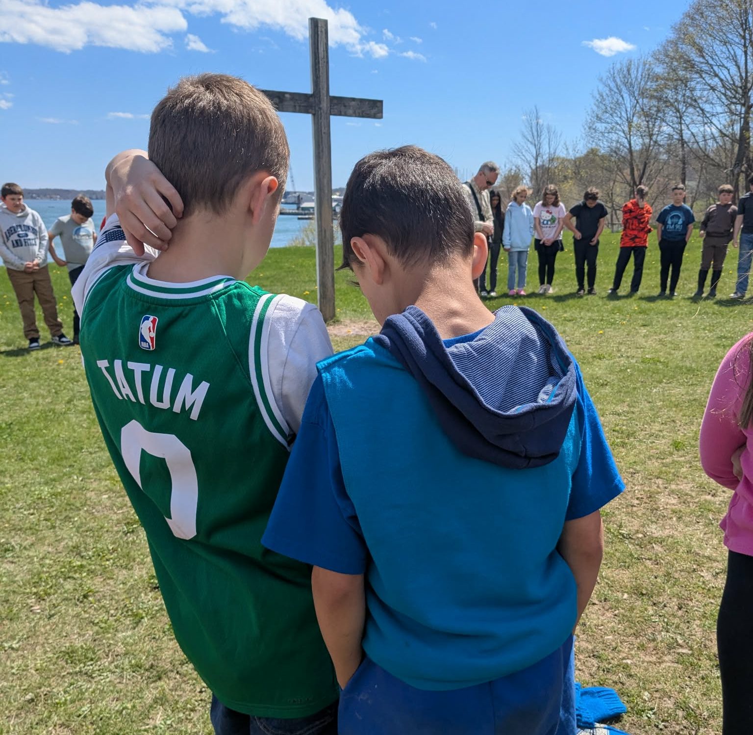 Four boys bowing their heads in prayer around an open Bible